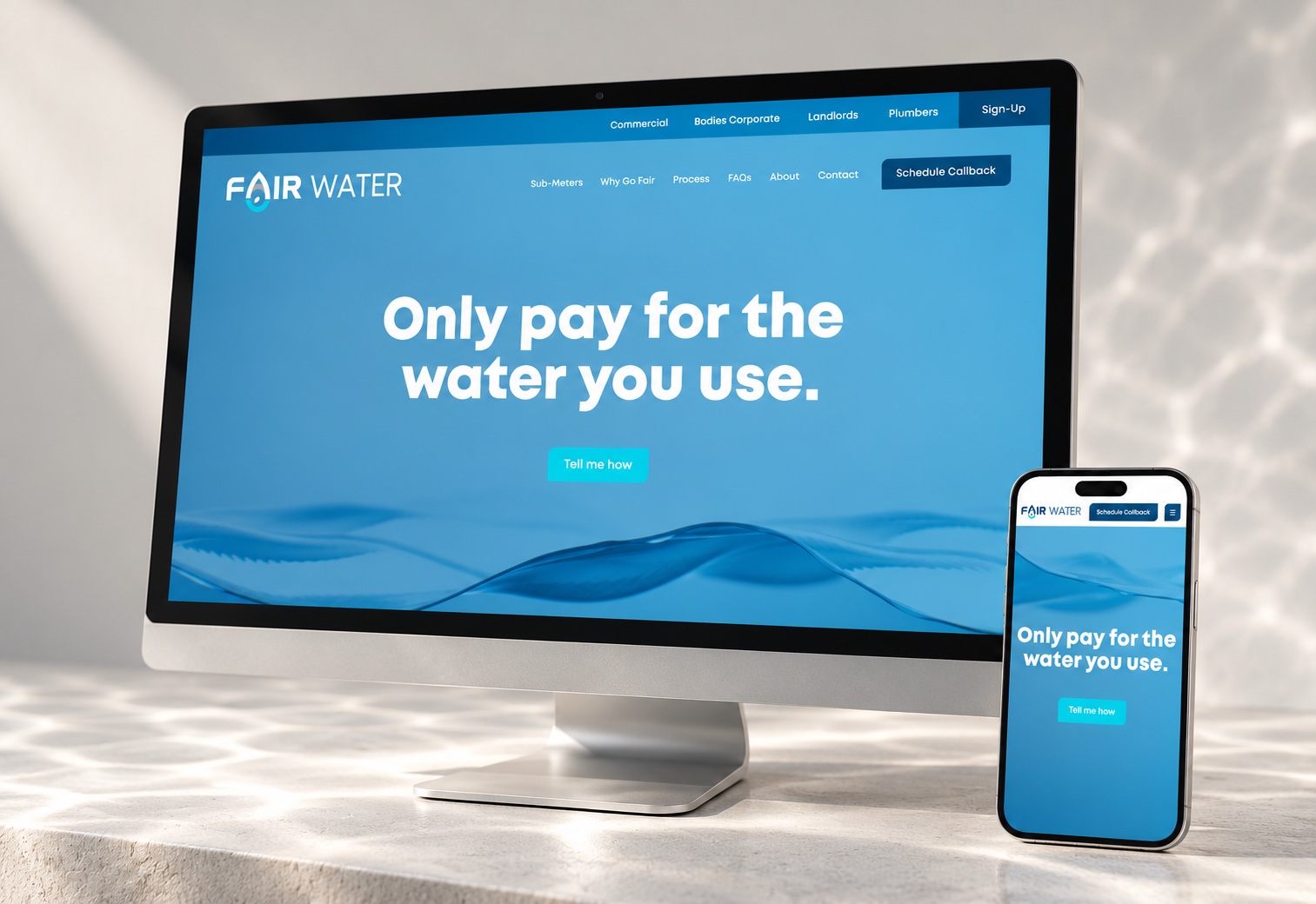 Fair Water Meters website displayed on a silver desktop monitor and phone, with a blue water background and soft studio lighting