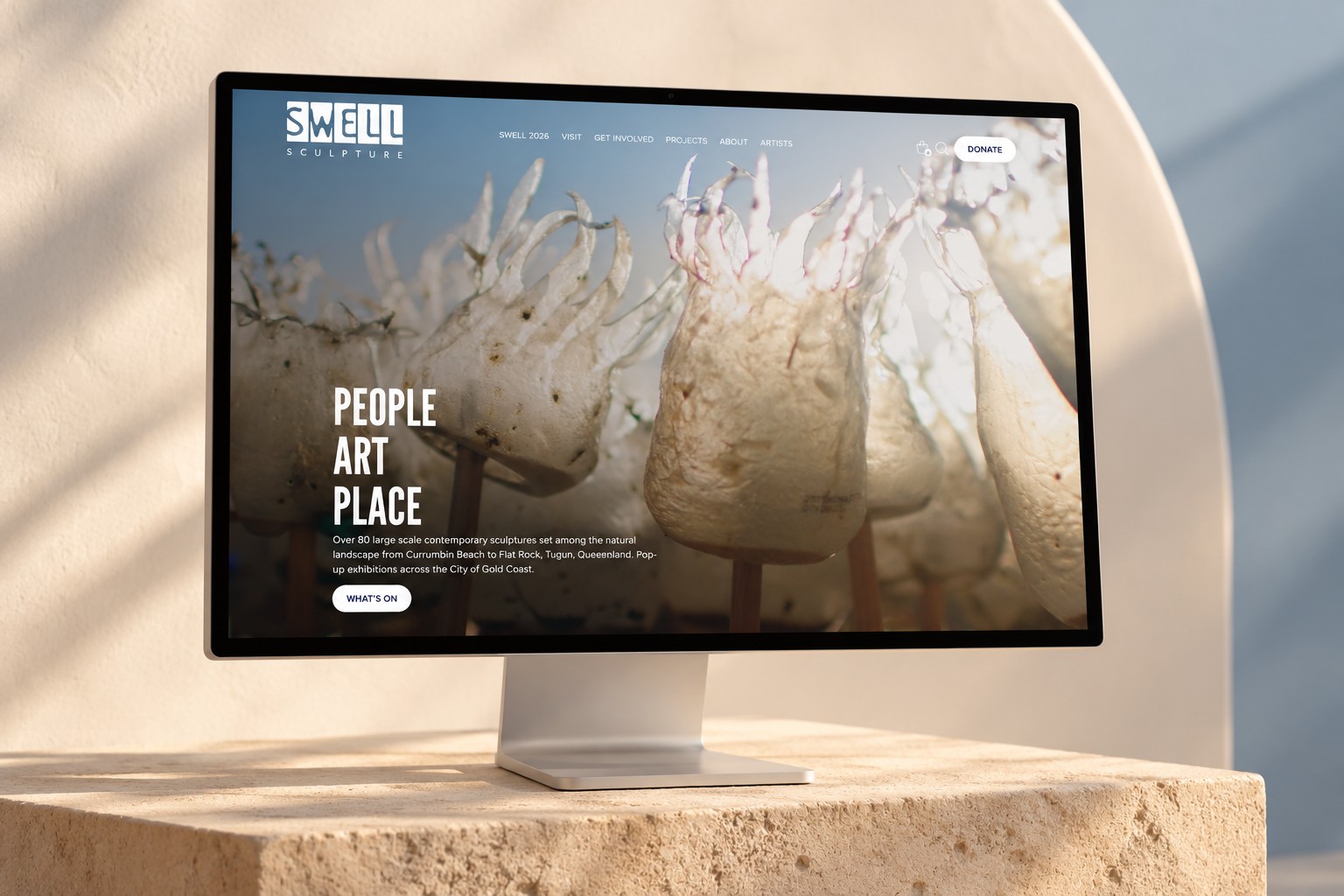 SWELL Sculpture Festival homepage displayed on a desktop monitor in a coastal gallery setting